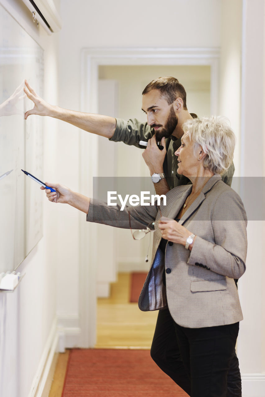 Senior woman explaining presentation to male colleague in office