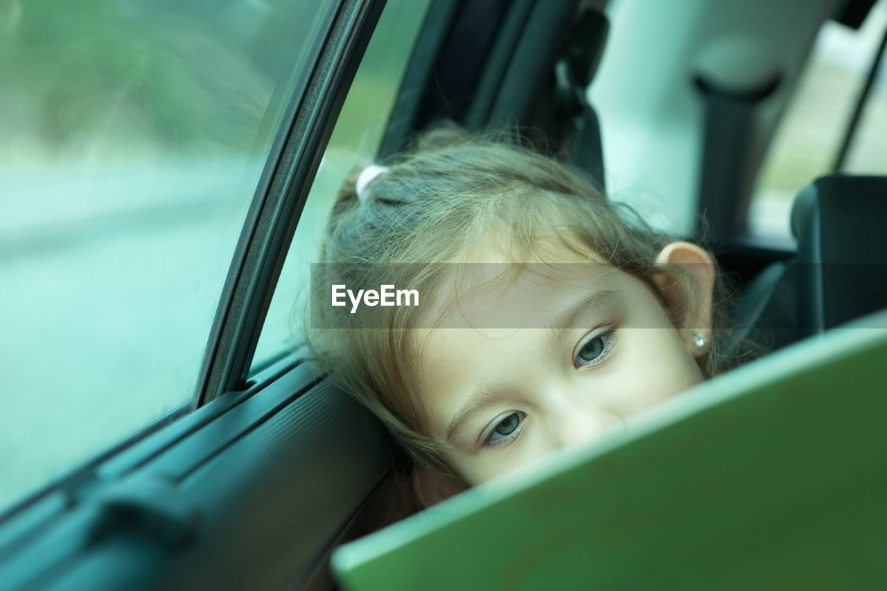 Cute girl reading book in car