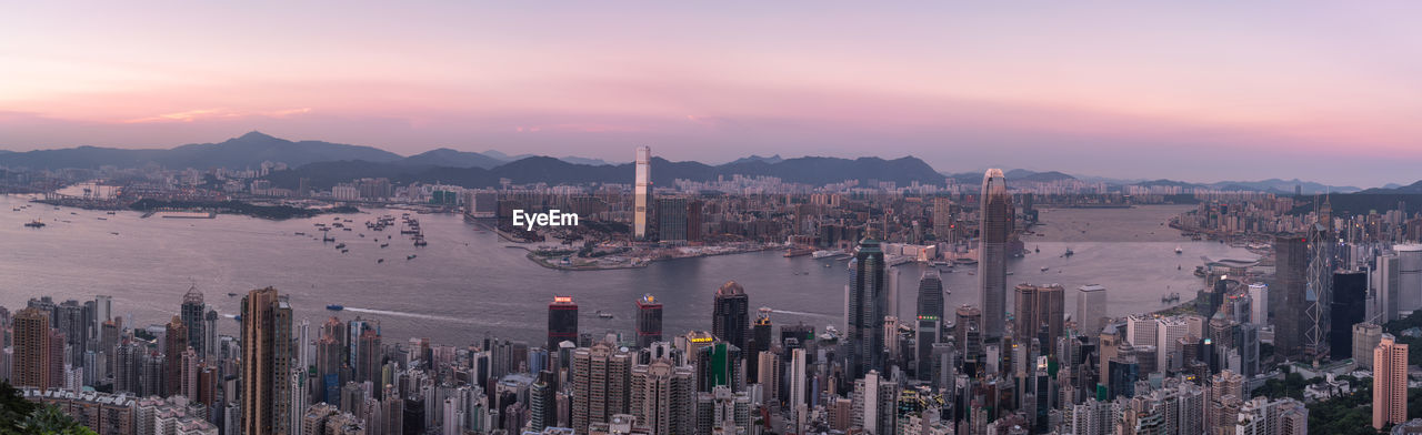 Panoramic view of cityscape by river against sky