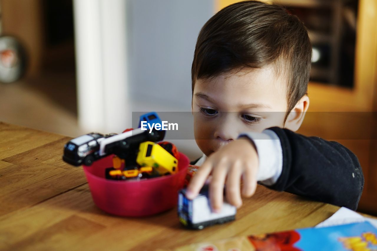 Close-up of boy playing with toy car at home