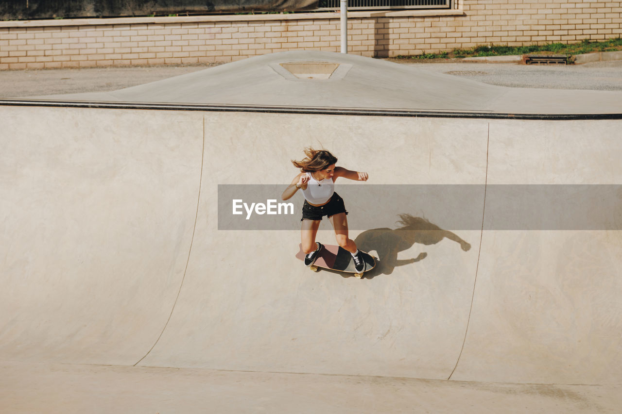 Young woman skateboarding on sports ramp