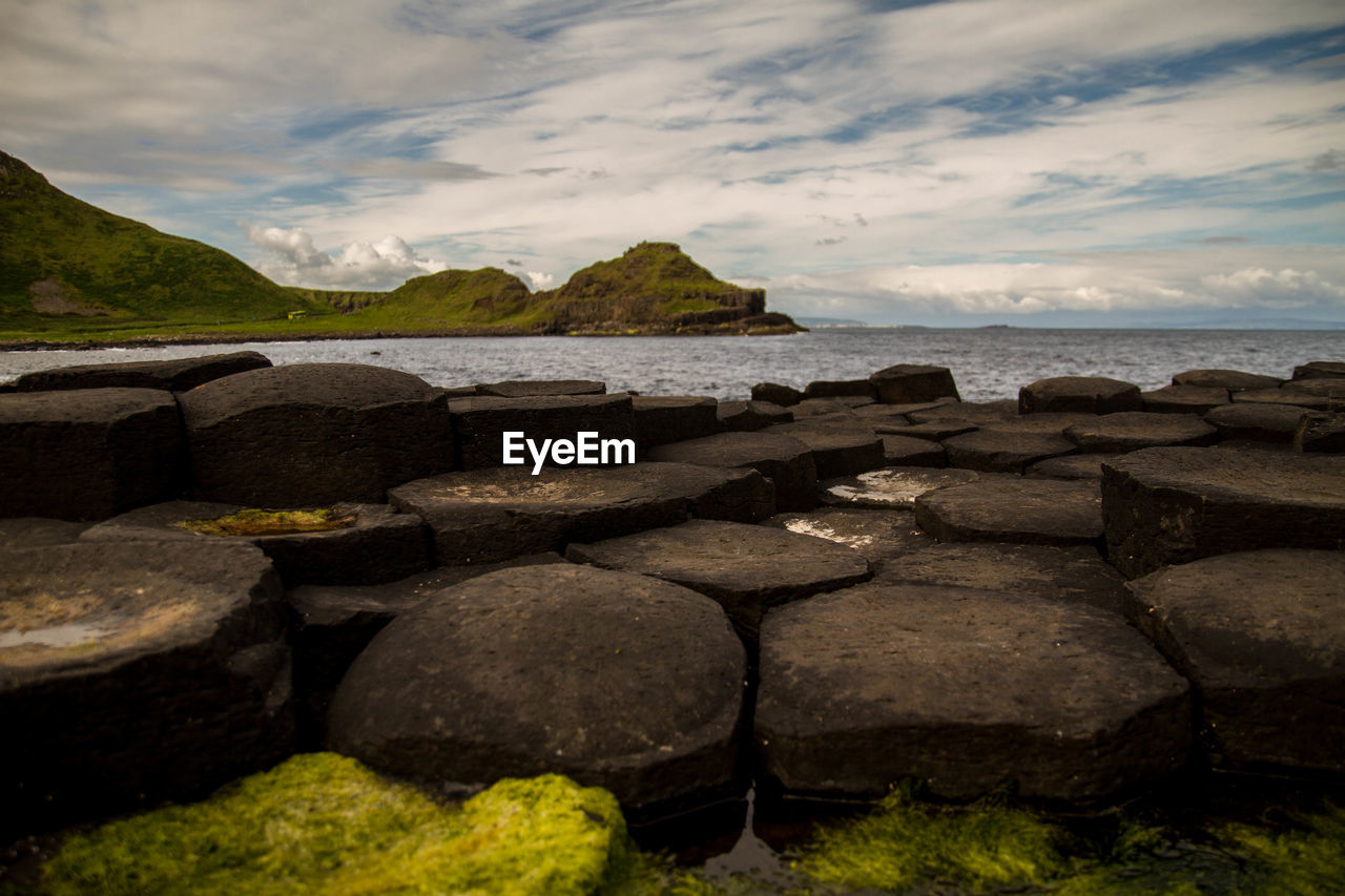 Rocks and sea against cloudy sky