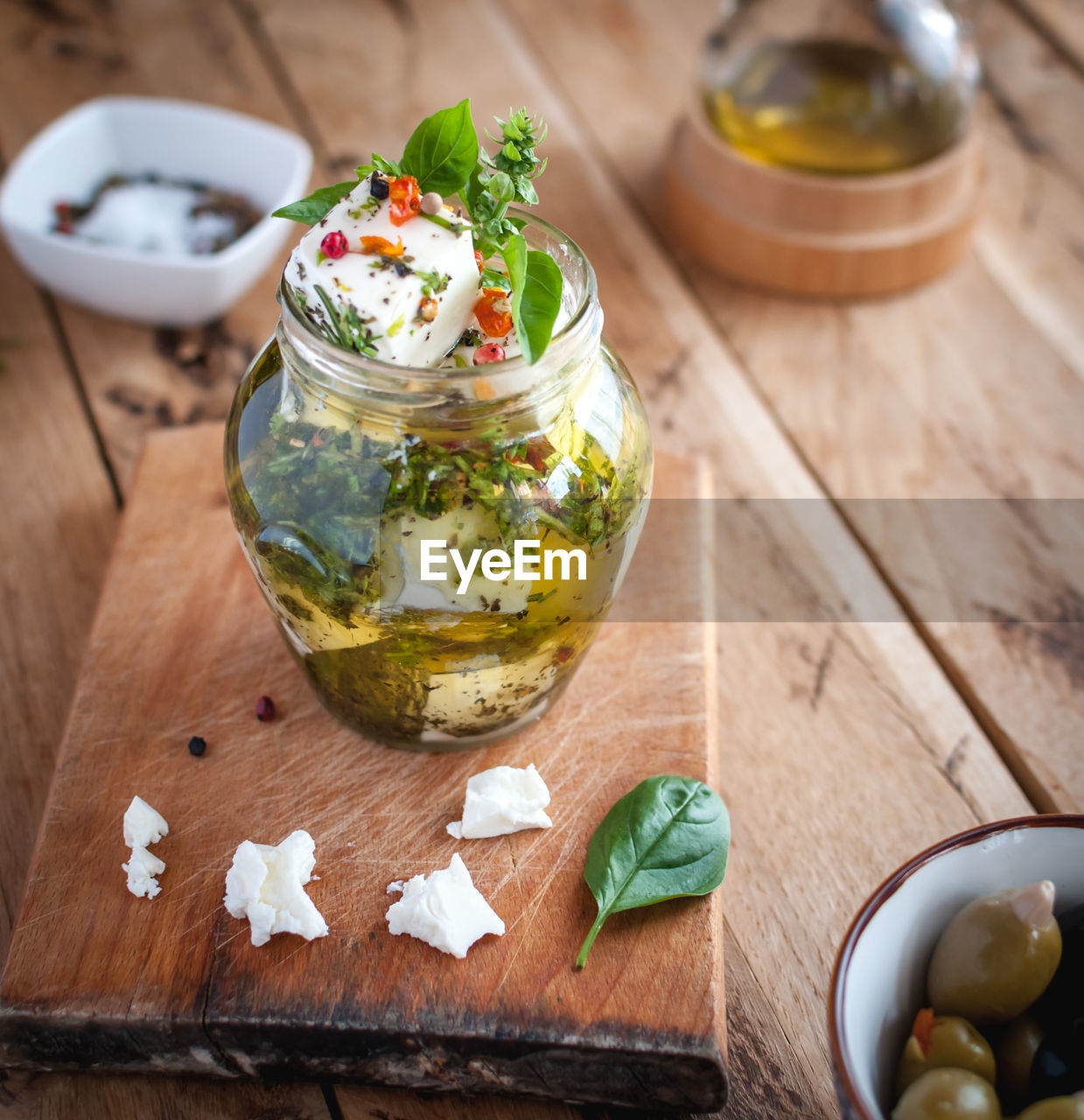 Marinated feta cheese in olive oil, herbs and red pepper flakes on wooden background