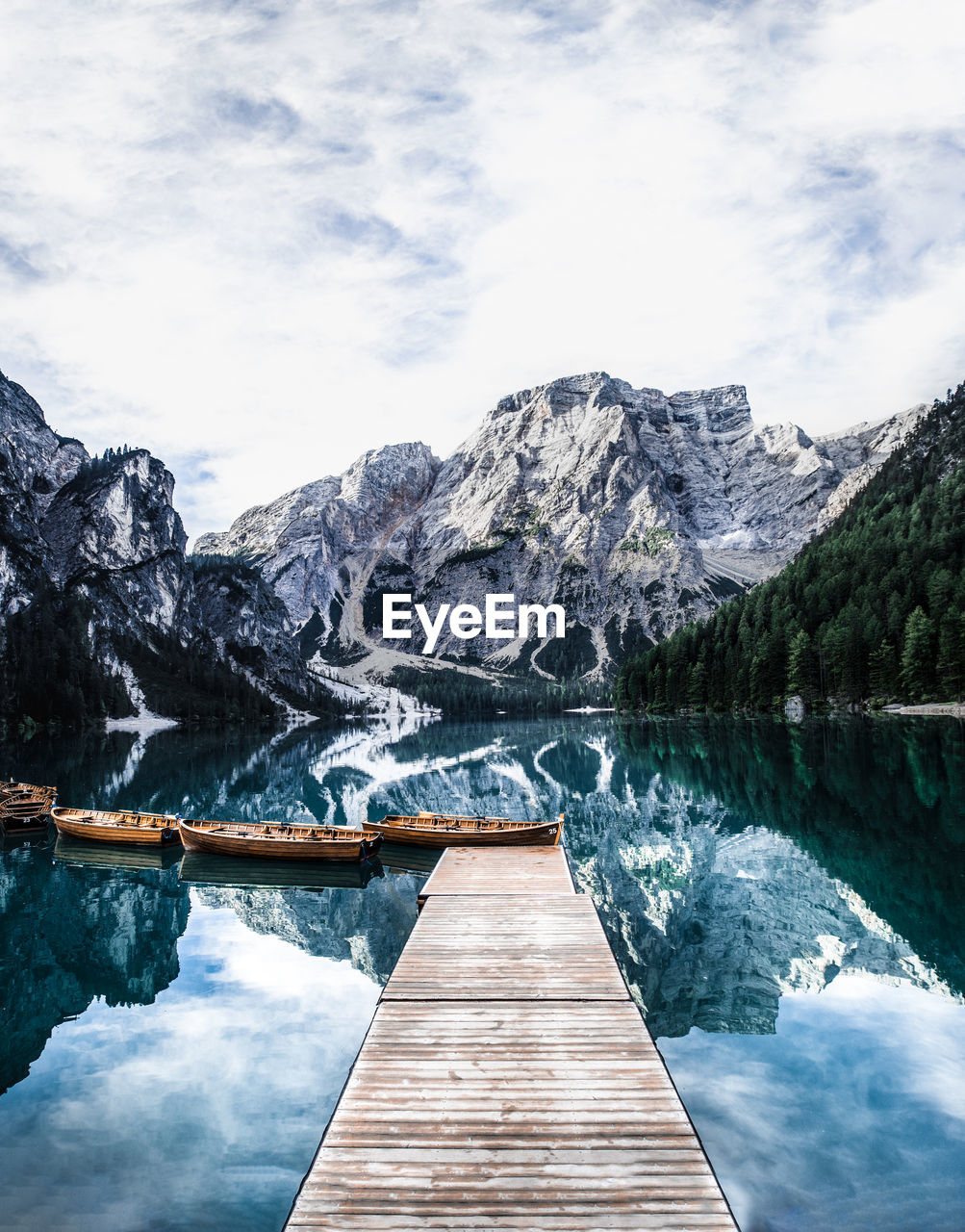 Boats in lake against snowcapped mountains