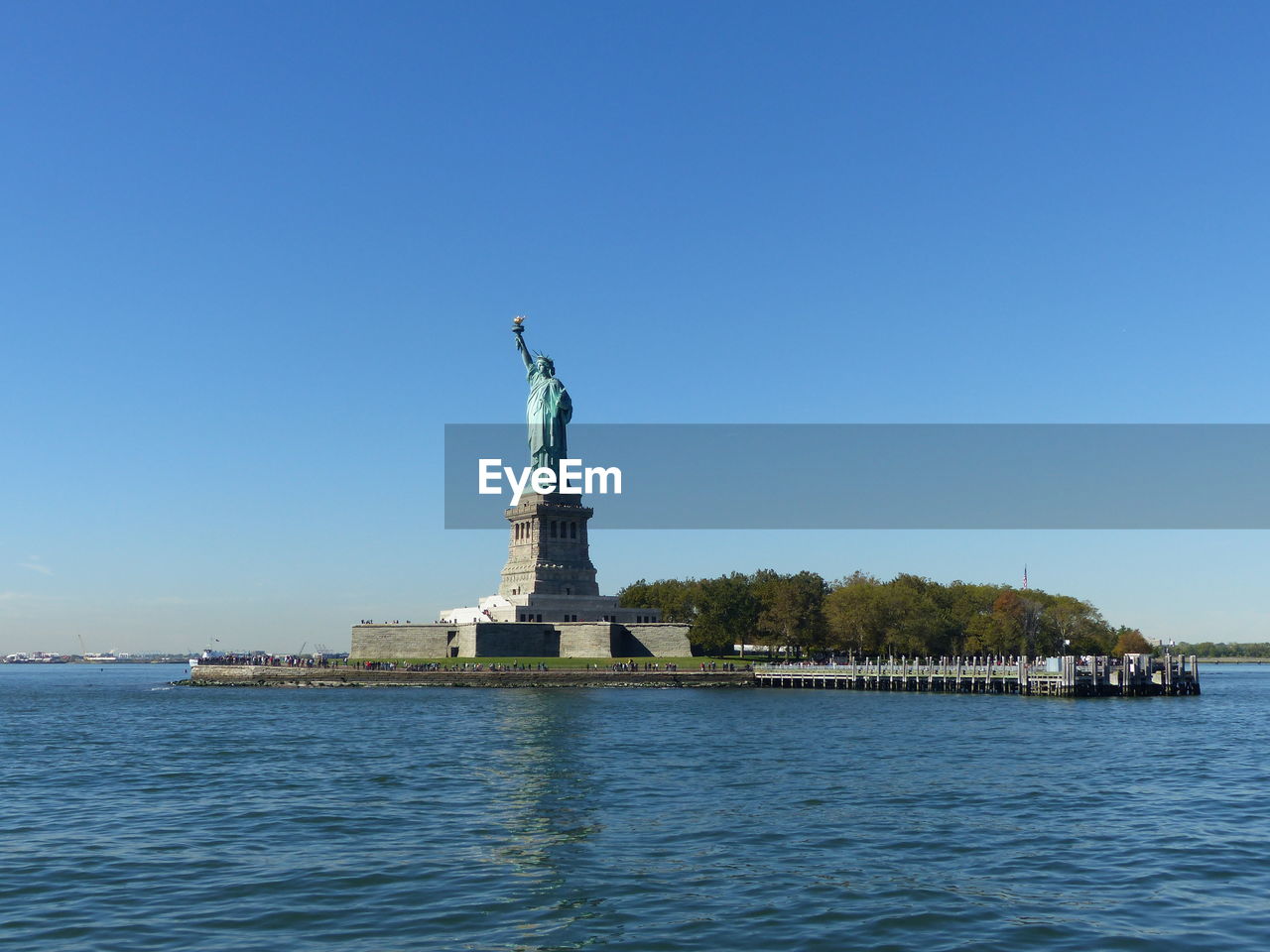 Statue of liberty by hudson river against blue sky