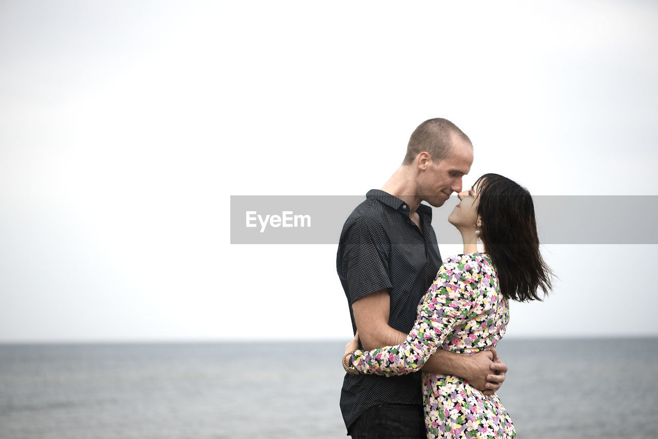 Young couple hug on the beach at runny summer day