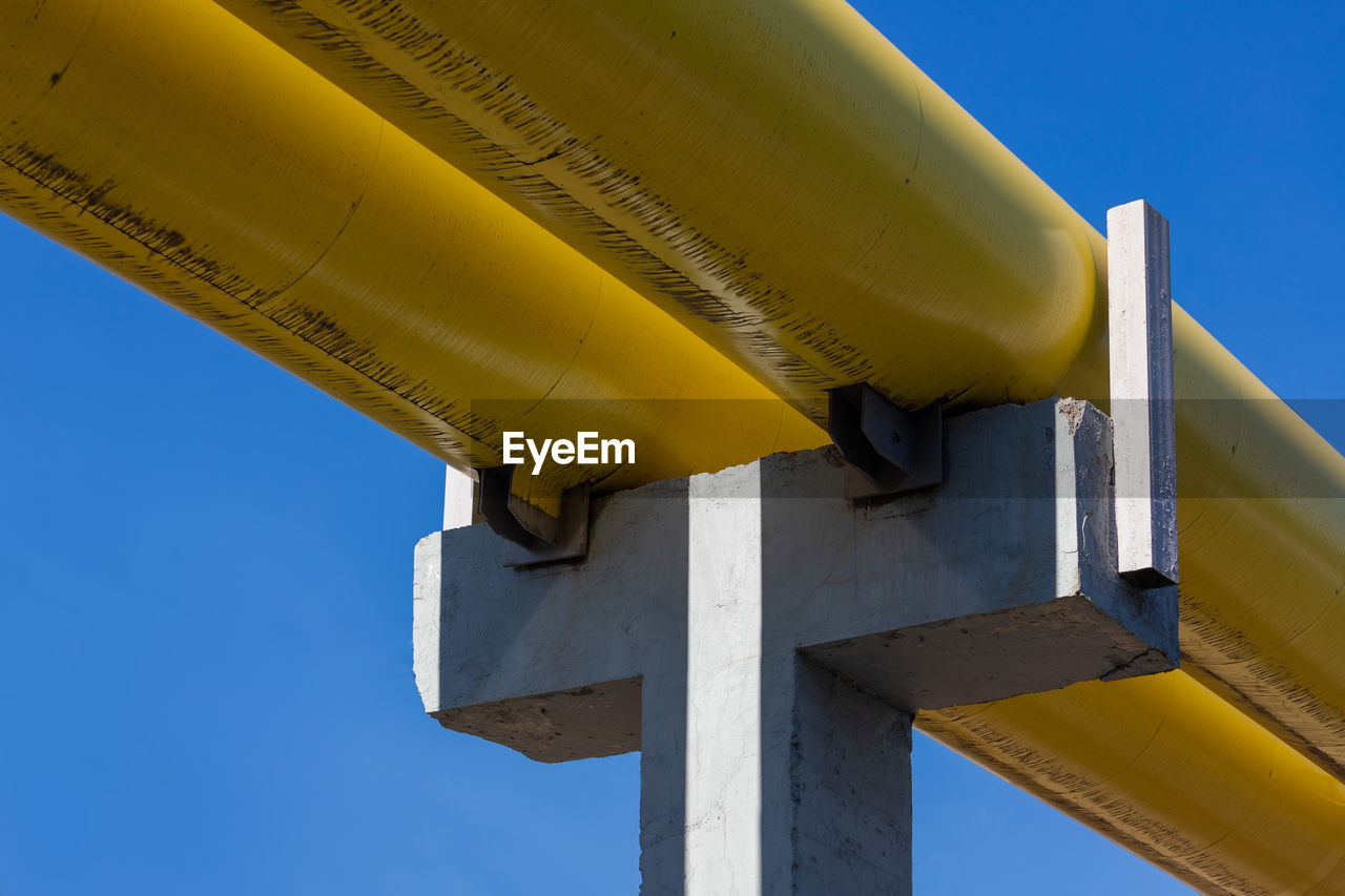 LOW ANGLE VIEW OF YELLOW PIPE AGAINST SKY