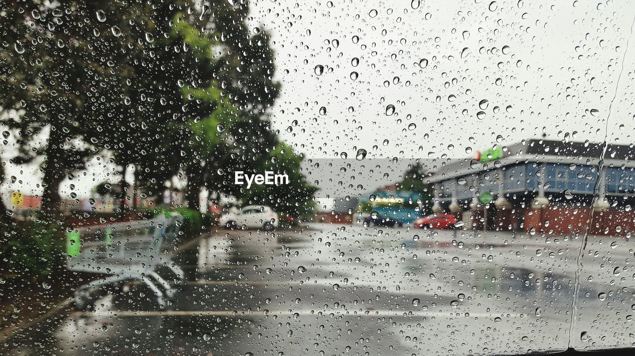 Road seen through wet car windshield during rainy season