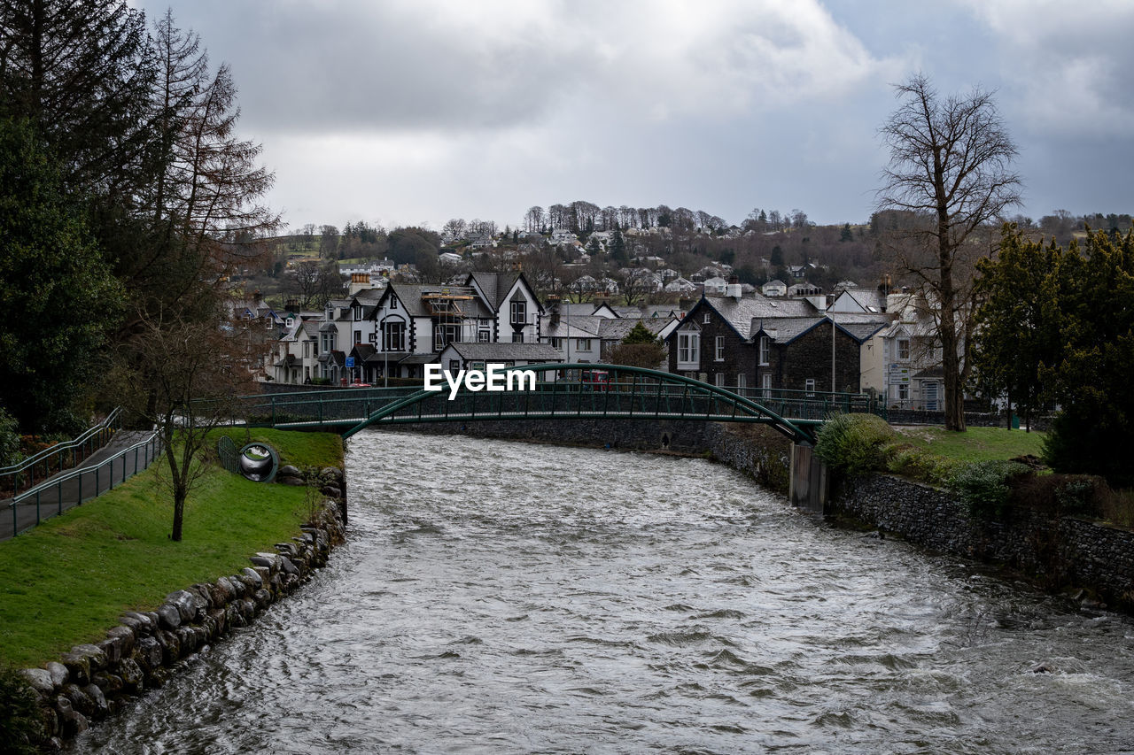 Bridge over river by town against sky