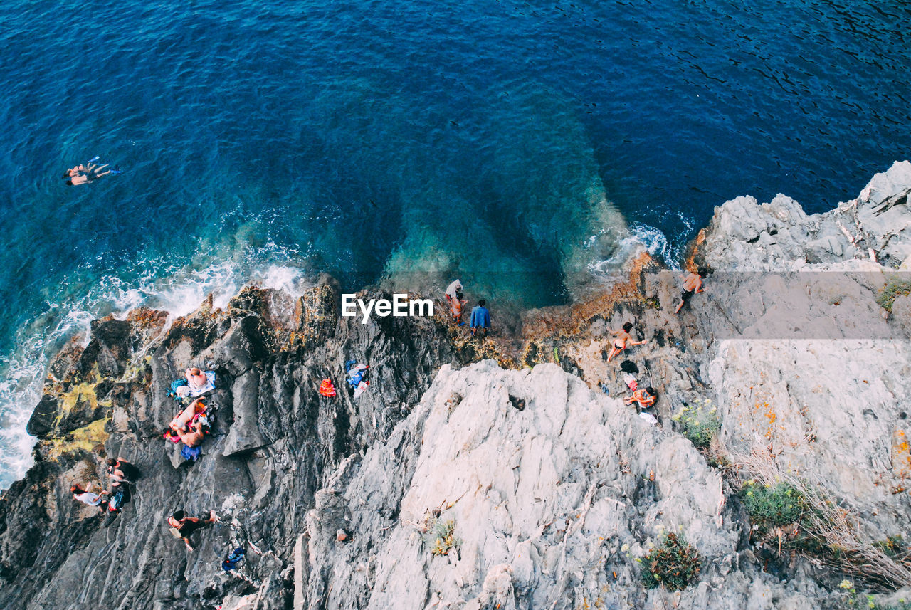 High angle view of people on rocks by sea