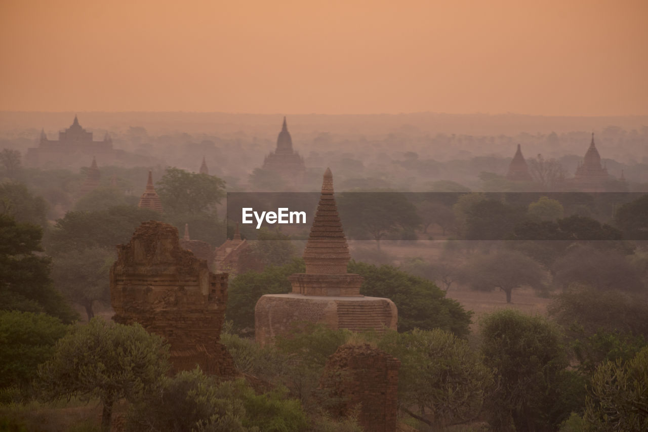 Stupas against orange sky during sunset