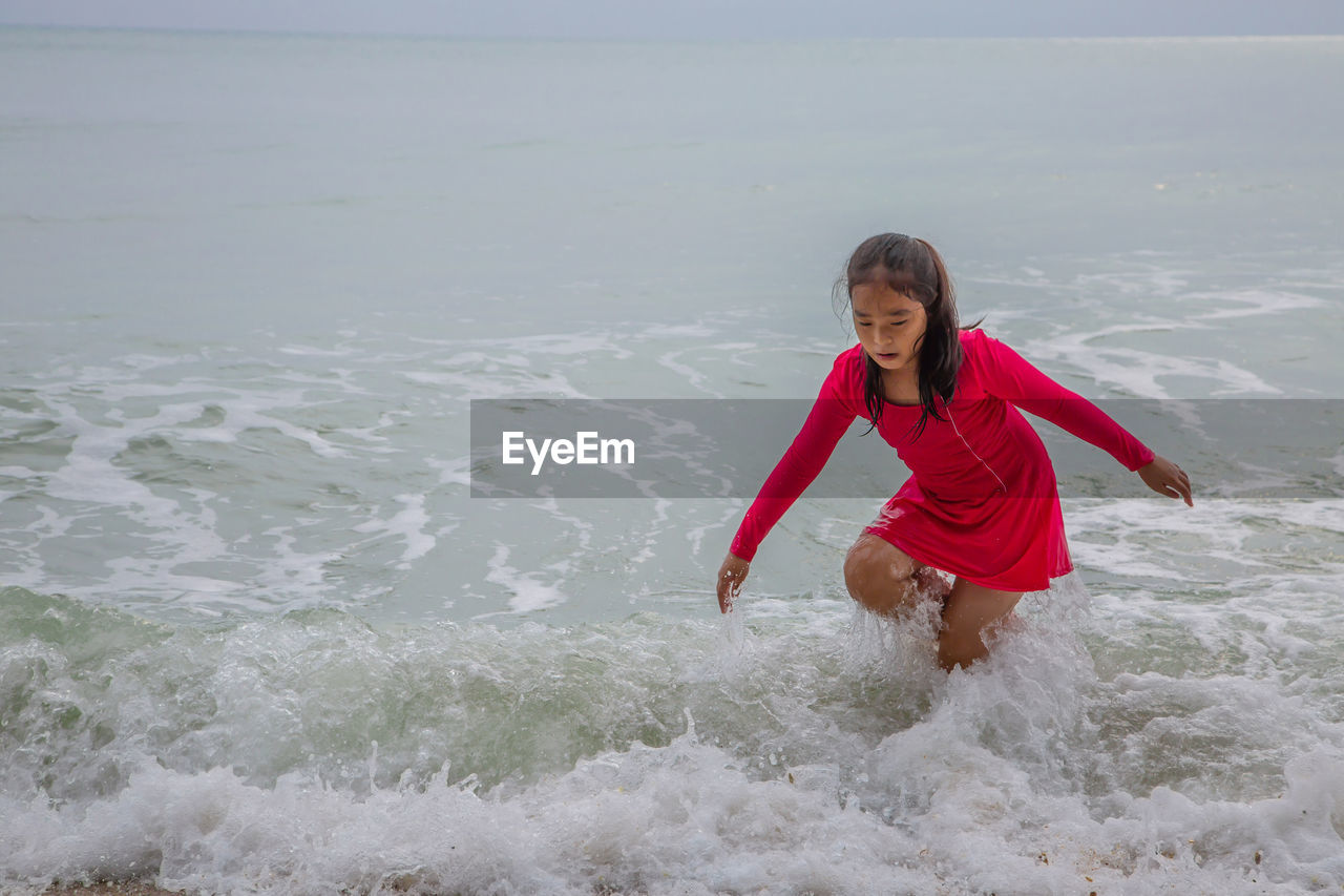 Girl running in sea against sky