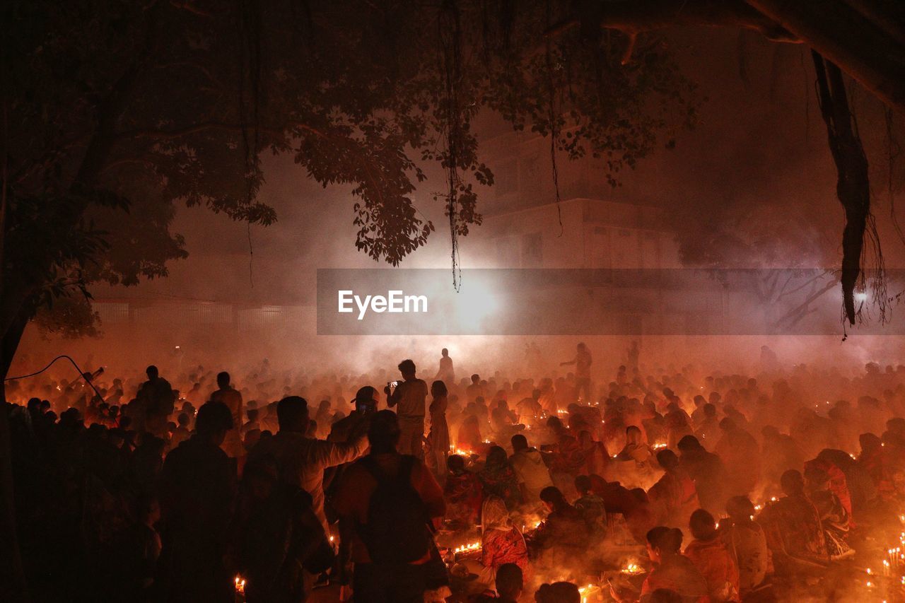 People are praying at rakher upobash under big tree in a smokey environment