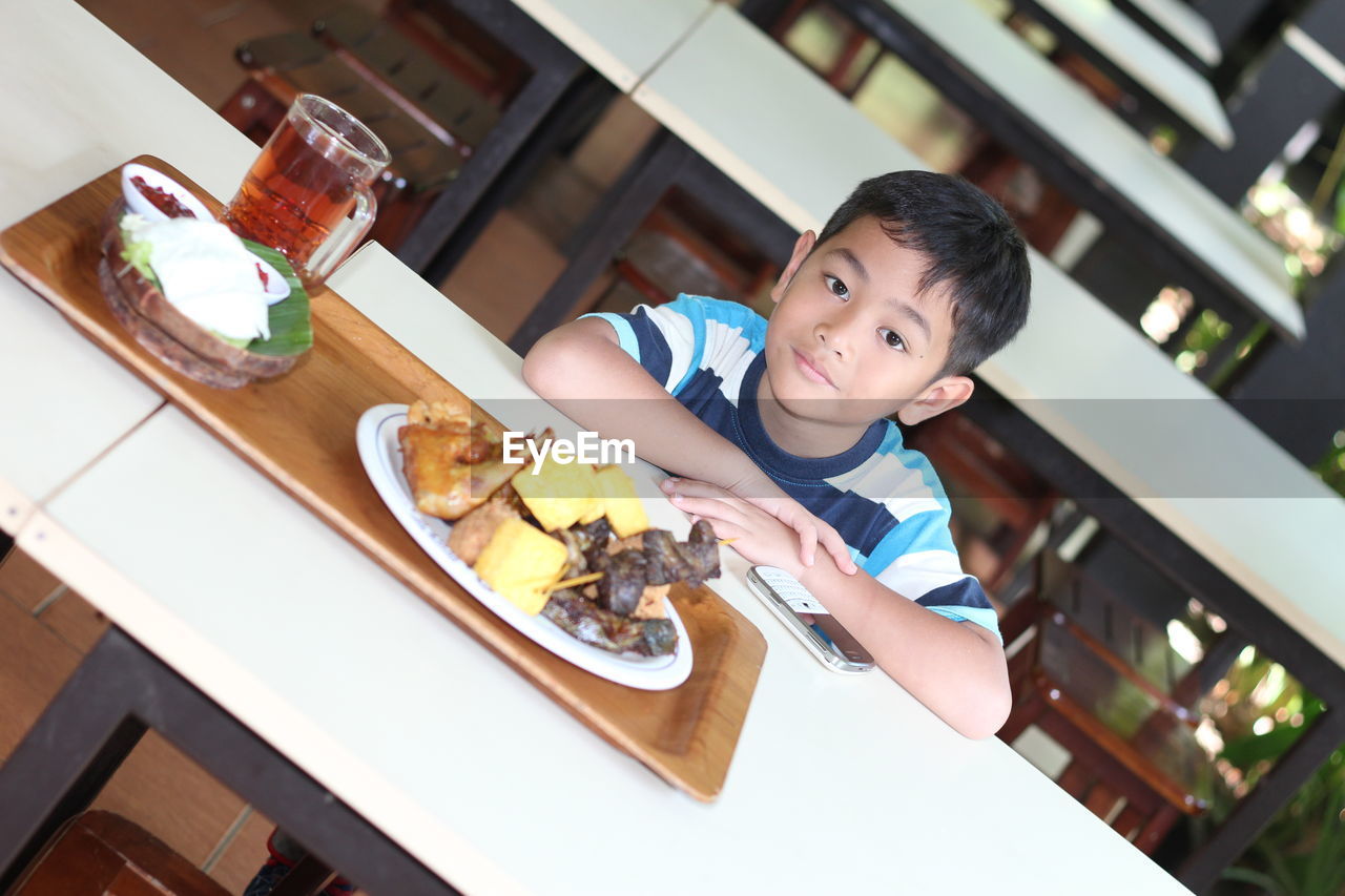 High angle view of boy with food on table sitting in restaurant