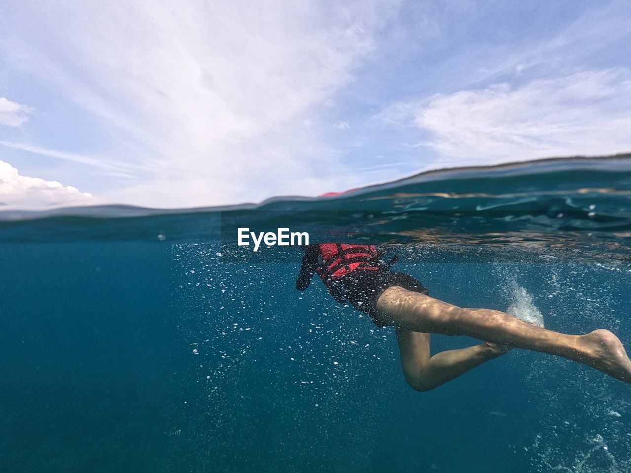 Low section of person swimming in sea against sky