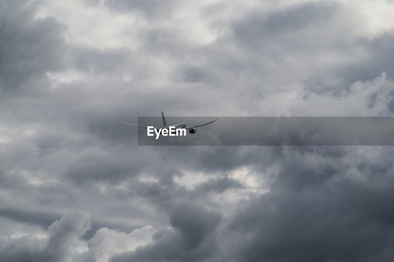 Low angle view of airplane flying in cloudy sky