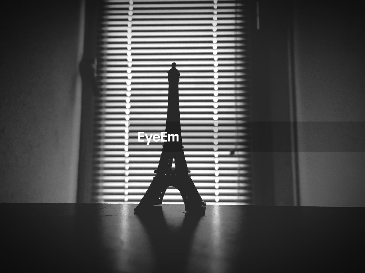 Close-up of eiffel tower souvenir on table against window blinds