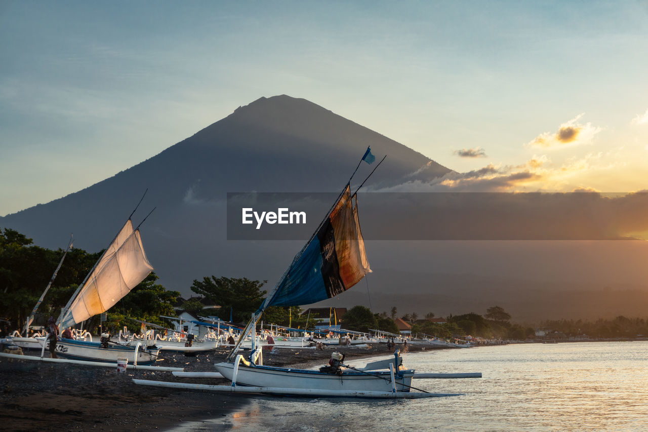 Sail boats at the coast of blacksand beach in amed, bali and mount agung volcano in the background