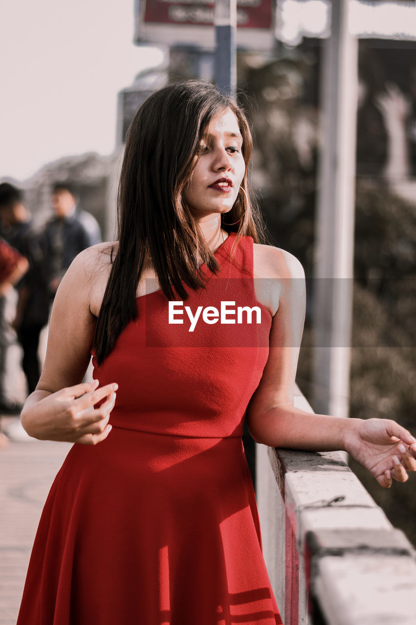 Young woman looking away while standing by railing