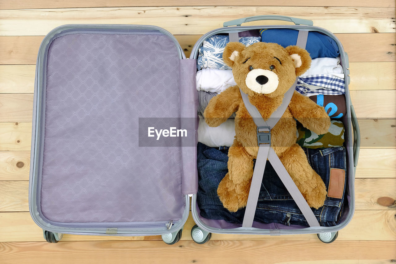 High angle view of teddy bear and clothes in suitcase