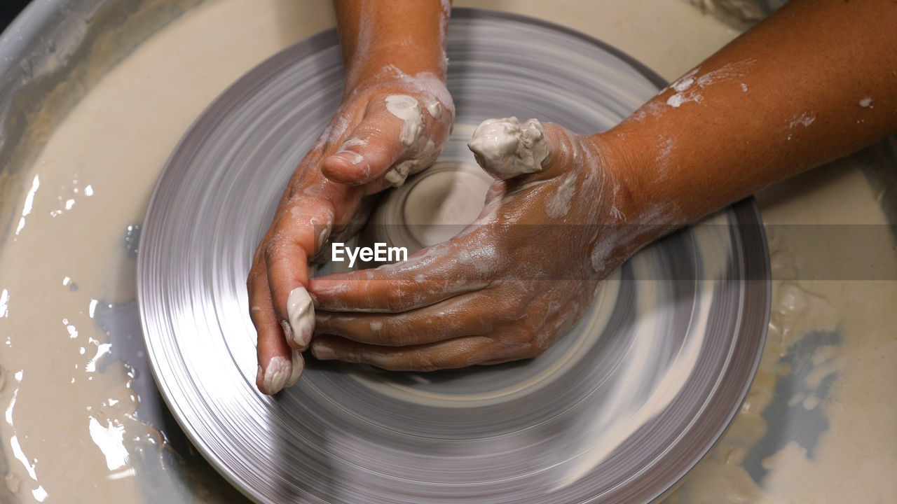 Close-up of a woman's hands dyed with clay. work at a pottery wheel in a pottery workshop