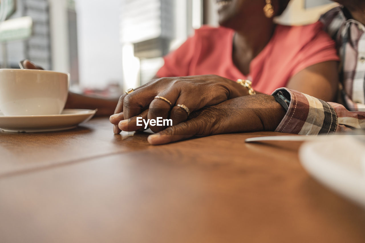 Senior couple holding hands at table in cafe