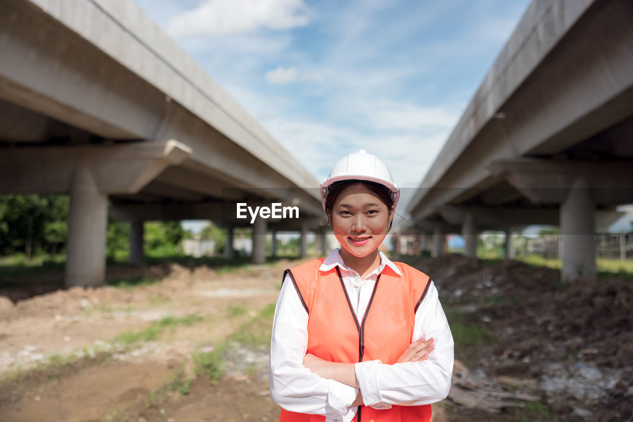 At a building site, a confident female construction worker poses for a portrait.