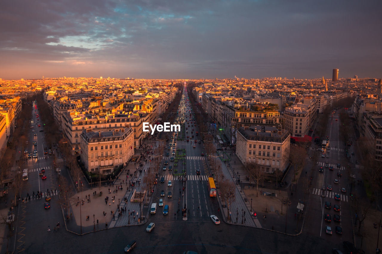 Drone view of urban house facades and roadways with transport under shiny cloudy sky at sundown in paris france