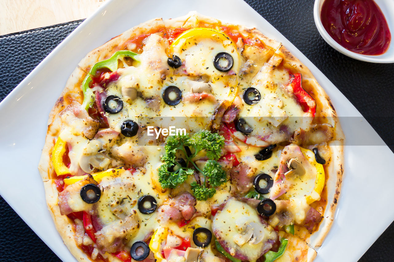 HIGH ANGLE VIEW OF PIZZA SERVED IN PLATE ON TABLE