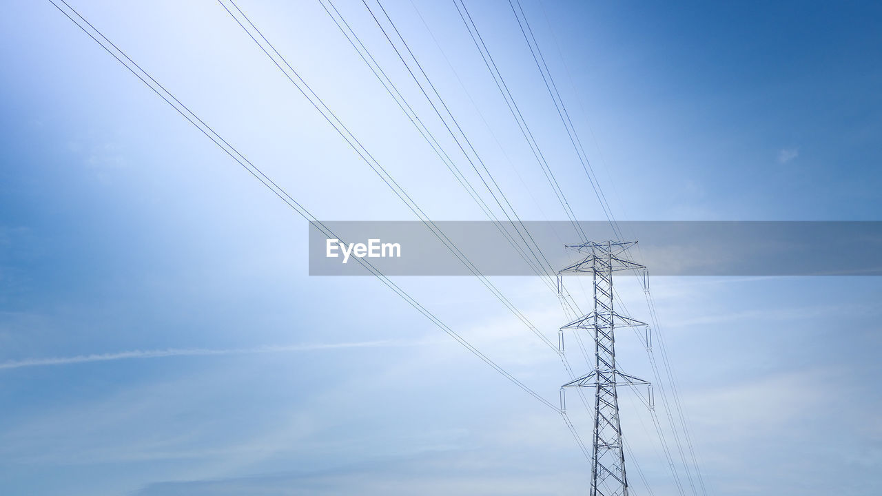 Low angle view of electricity pylon against blue sky