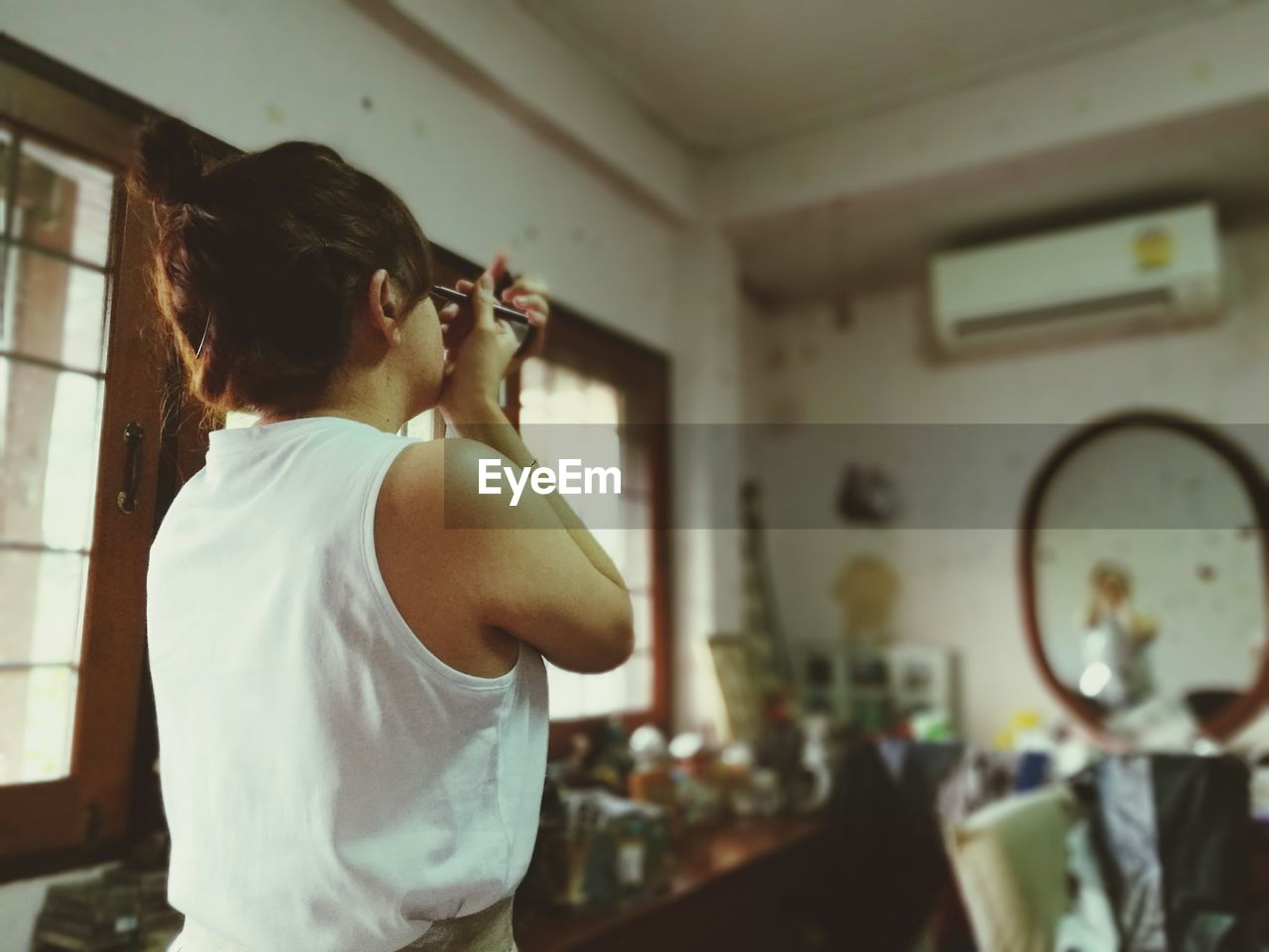 Rear view of woman applying eyeliner