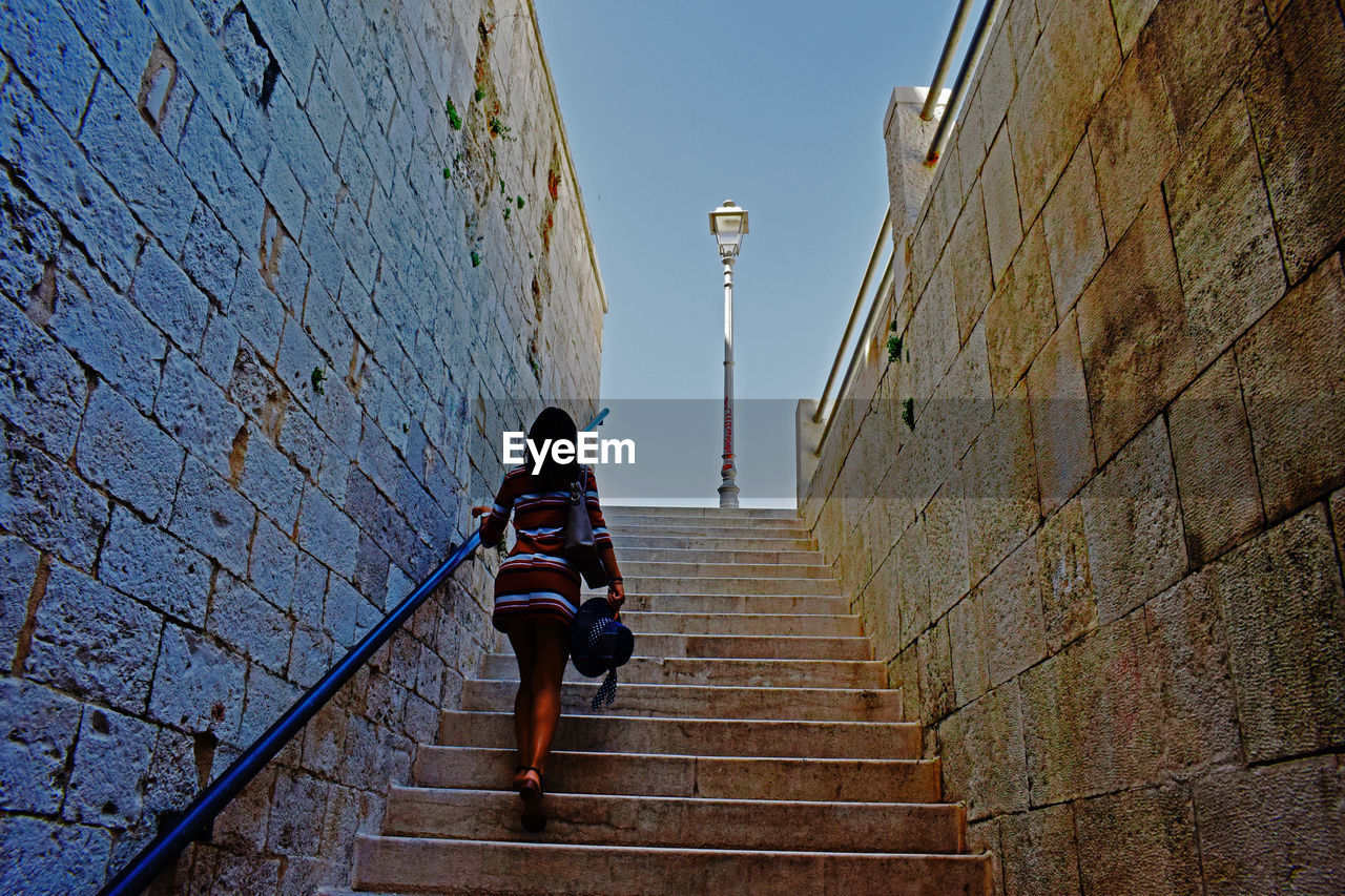 Rear view of woman moving up on steps