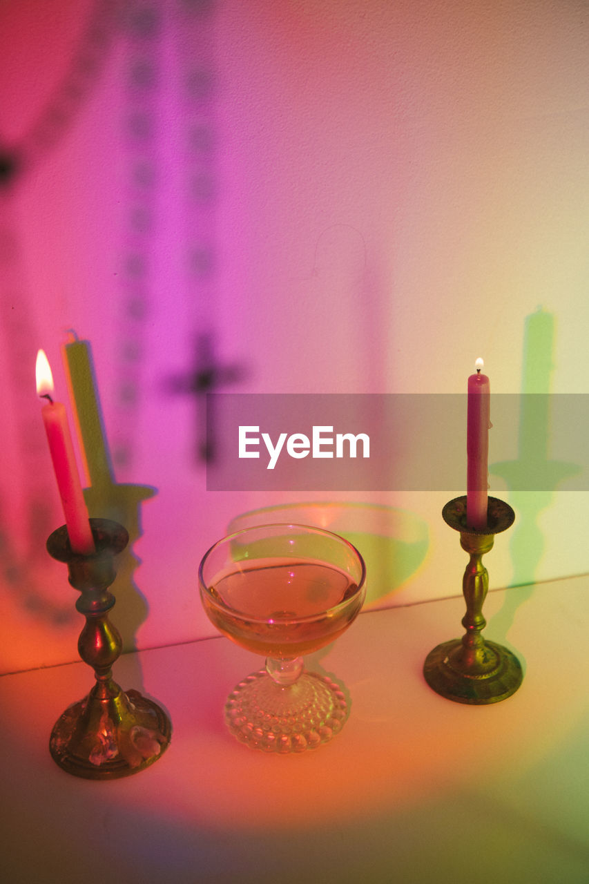 Colorful spell scene of wine and candles with cross rosary out of focus