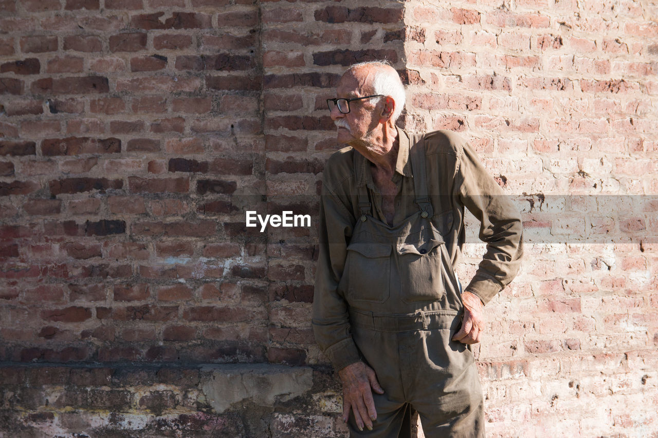 Portrait of old man against bricked wall