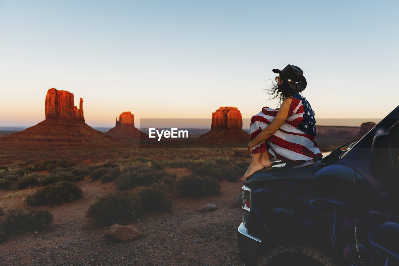 Usa, utah, woman with united states of america flag enjoying the sunset in monument valley
