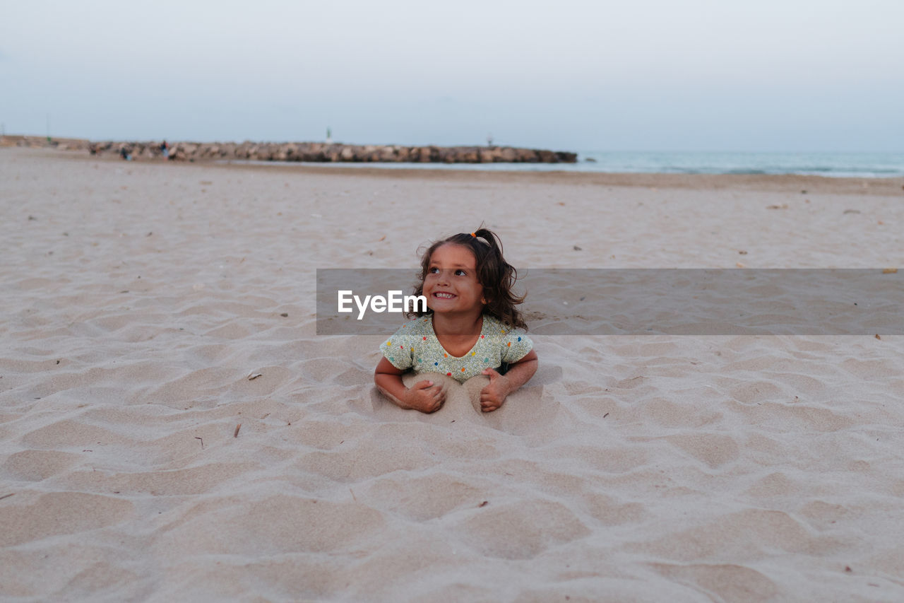 Smiling girl, lying on the sand on the beach