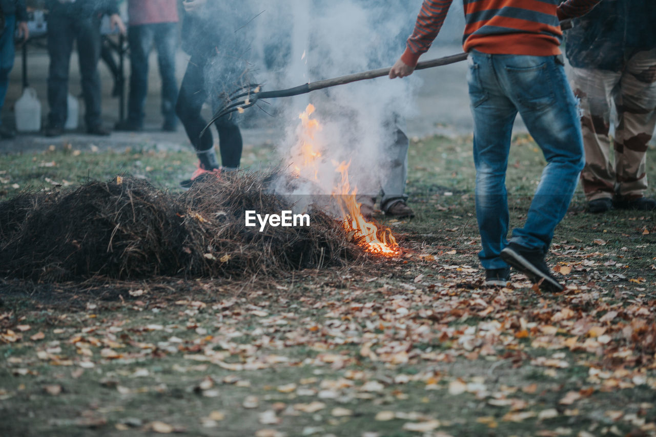 Low section of man burning hay on field