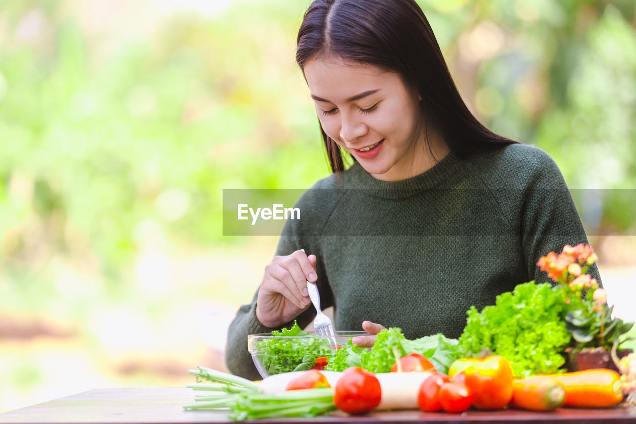 Smiling young woman having salad at outdoor restaurant