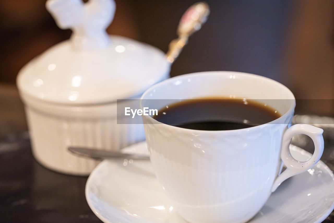 CLOSE-UP OF COFFEE CUP ON TABLE AGAINST WHITE BACKGROUND