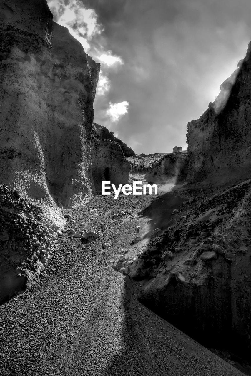 Rock formations by road against sky