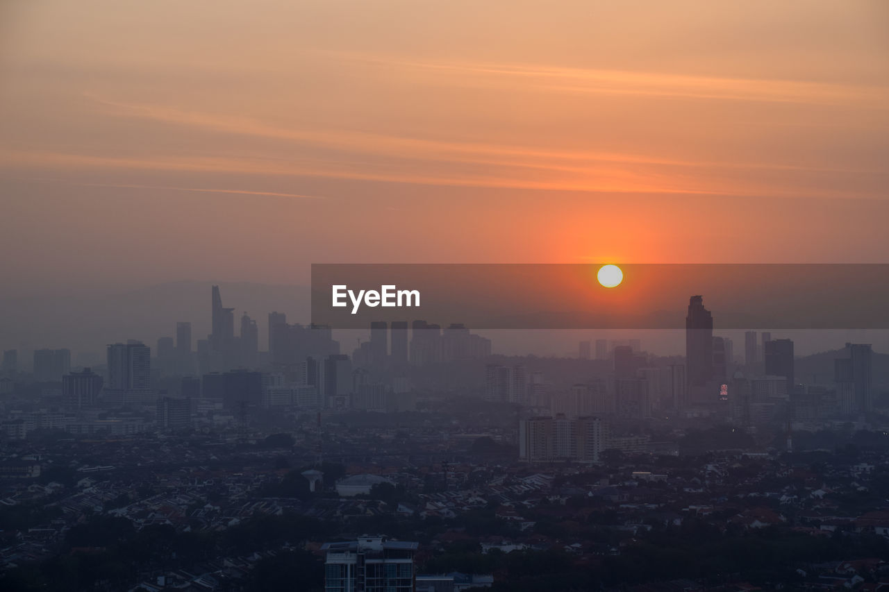 Modern buildings in city against sky during sunset