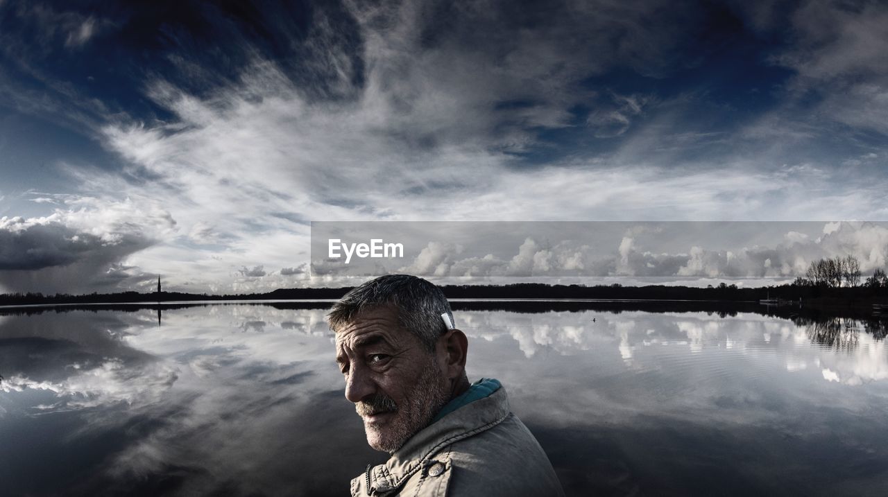 Side view portrait of man standing against lake with reflection