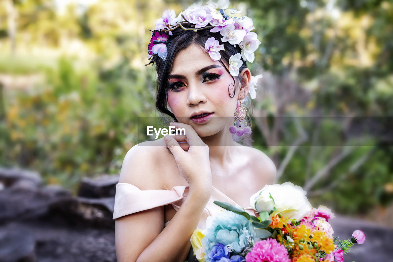 Portrait of beautiful bride with flowers at forest