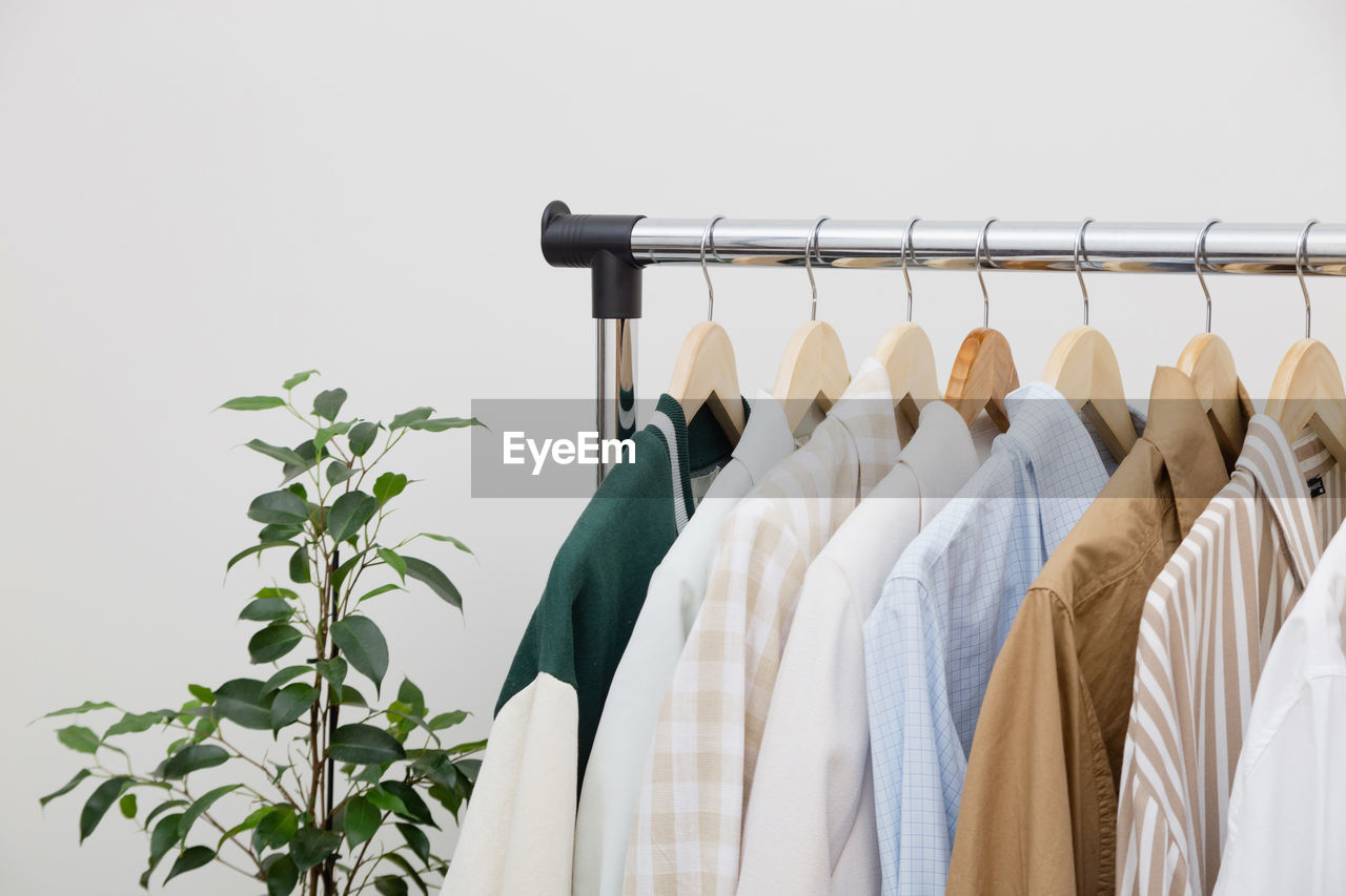 coathanger, hanging, clothing, rack, clothes rack, fashion, variation, retail, indoors, no people, button down shirt, in a row, business, shopping, white, group of objects, store, large group of objects, lifestyles, closet, furniture, textile, dress, order, plant, consumerism, studio shot