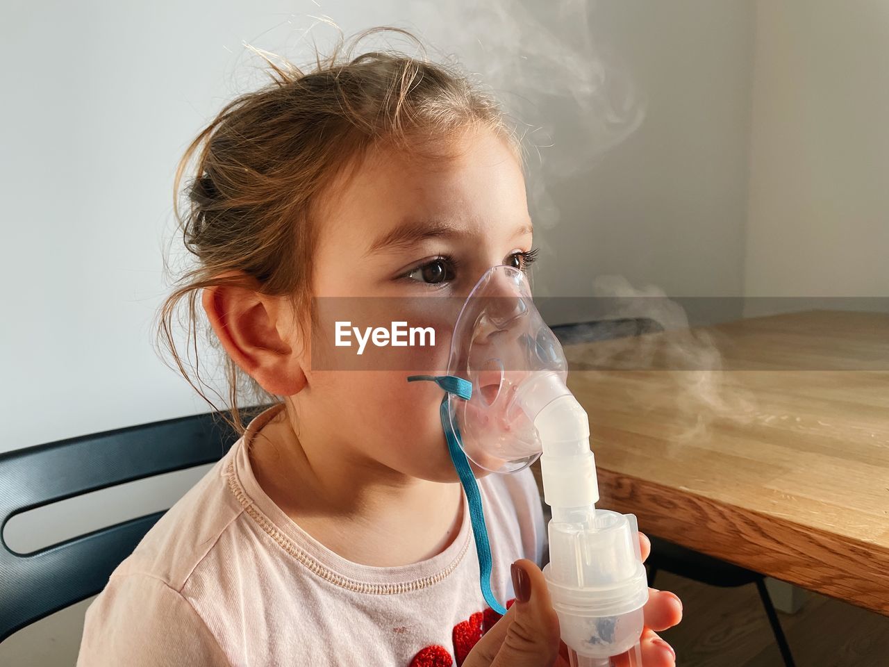 Cute girl wearing nebulizer at clinic