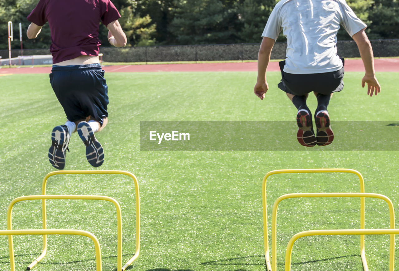 Rear view of people jumping over hurdles