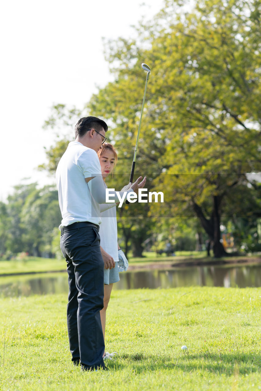 Full length of couple playing golf on field