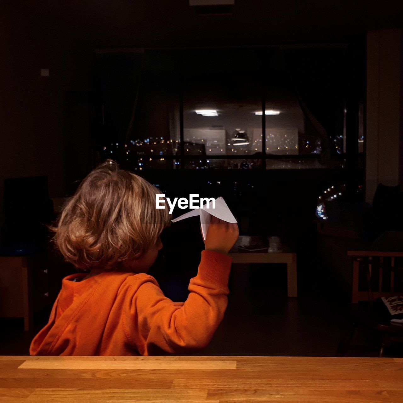 Rear view of boy playing with paper airplane at home