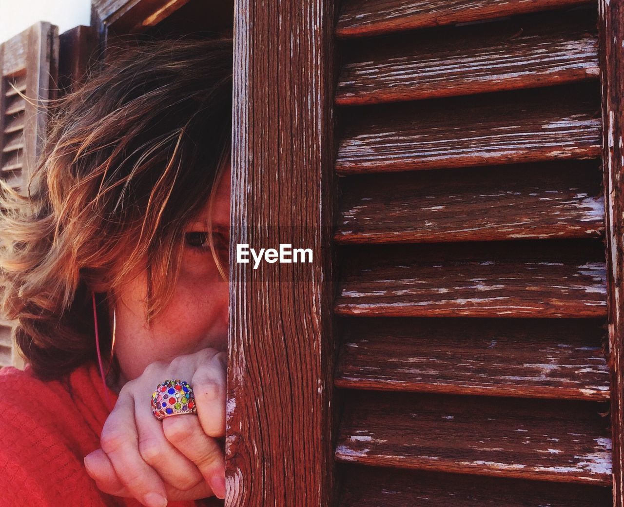 Portrait of woman hiding by wooden door