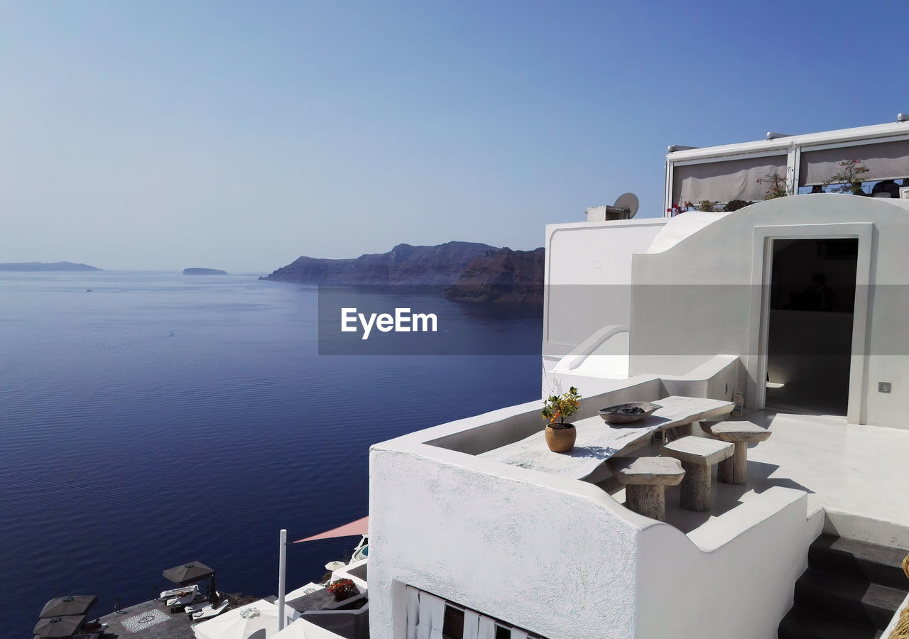 Outdoor house terrace roof with wooden vintage table and stool with sea view against mountains 